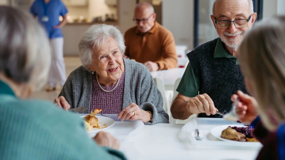 Senior living residents talking over lunch at a shared dining table